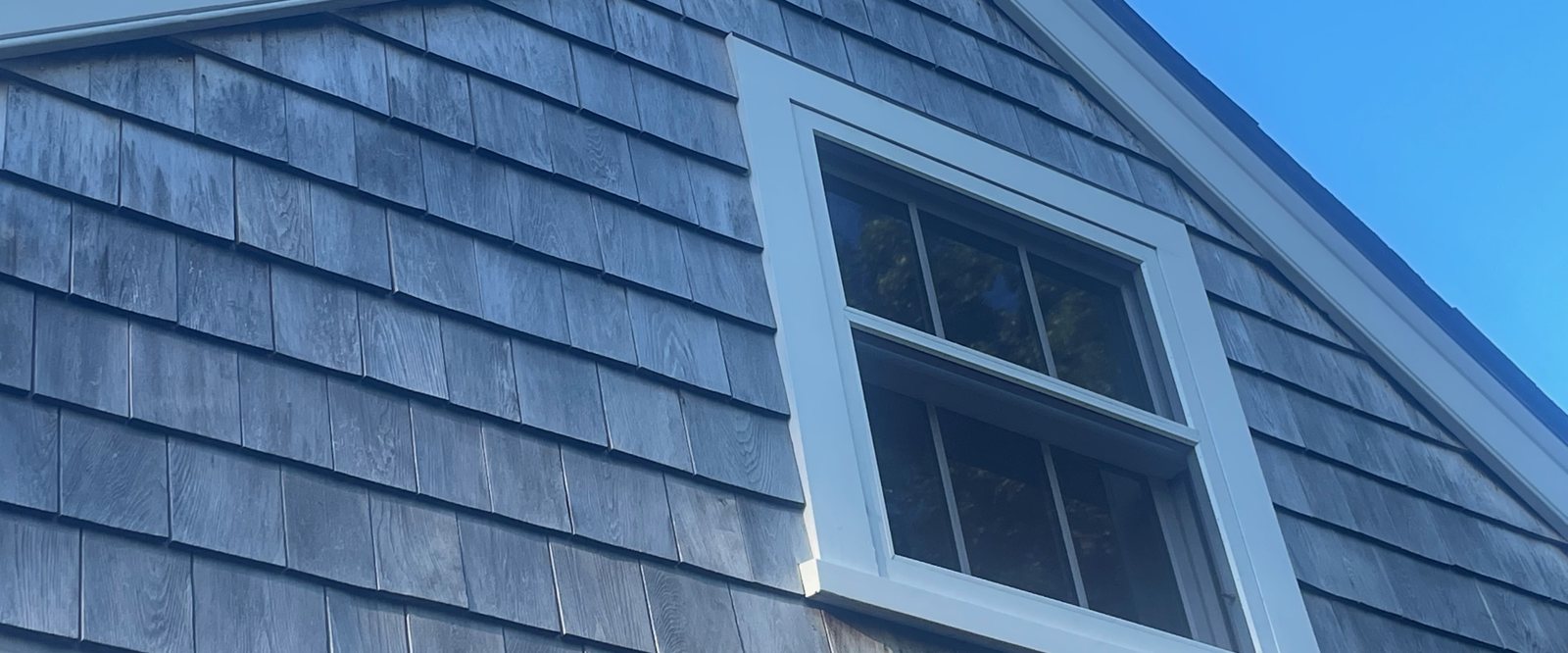 Weathered cedar shingles and a white-trimmed window on a Nantucket gable